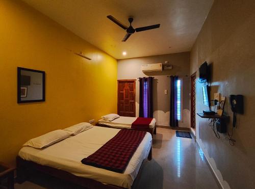 a bedroom with two beds and a ceiling fan at Art Le Cafe in Auroville