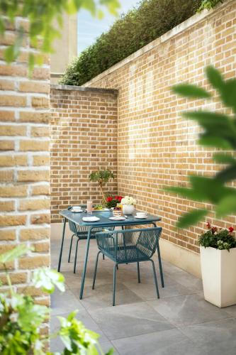 a table and chairs on a patio with a brick wall at COMO Metropolitan London in London