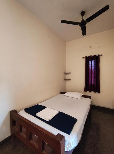 a bedroom with a bed with a ceiling fan at Art Le Cafe in Auroville