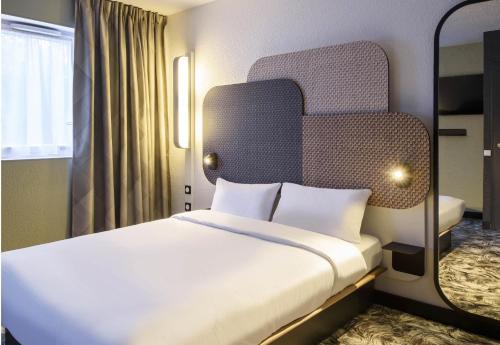 a hotel room with a bed with a head board at B&B HOTEL Viry-Châtillon in Viry-Châtillon