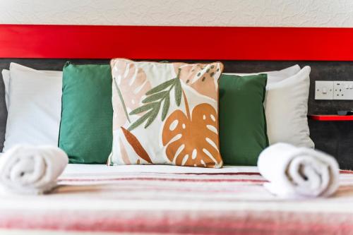 a bed with green pillows and a red headboard at Stylish Dudley Studio with Kitchen and Parking in Dudley