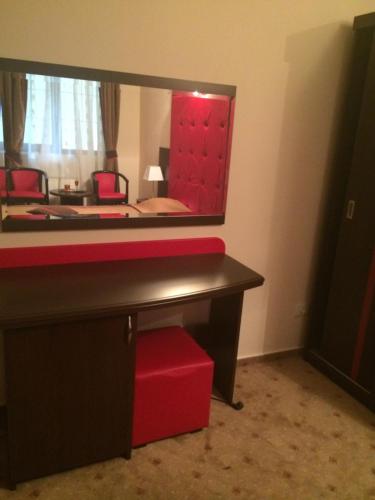 a room with a red desk and a mirror at Hotel Fiama in Oţelu Roşu
