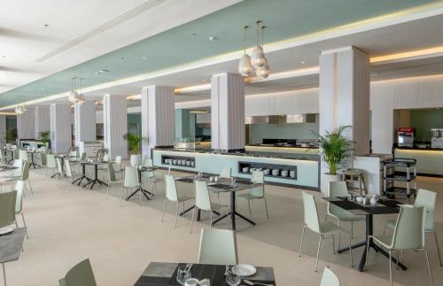 a restaurant with tables and chairs and a kitchen at Pickalbatros Palais Des Roses - Agadir - All Inclusive in Agadir