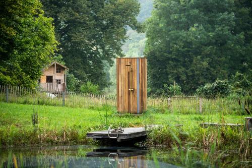 a wooden outhouse in a field next to a body of water at Gut Alt Necheln in Brüel