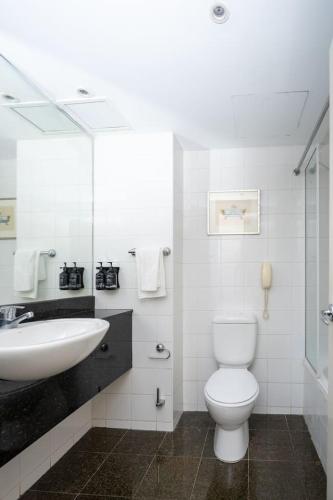a white bathroom with a sink and a toilet at Studio Retreat in the Heart of Parramatta in Sydney