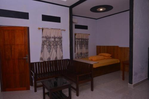 a bedroom with a bed and a bench in it at Homestay & Resto 88 in Dondo