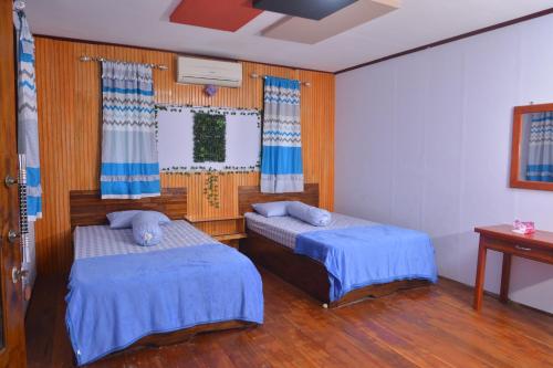two beds in a room with wooden walls and wood floors at Homestay & Resto 88 in Dondo