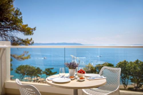 a table on a balcony with a view of the ocean at Girandella Resort, Valamar Collection in Rabac