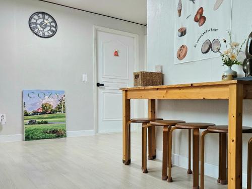 a table and stools in a room with a clock on the wall at Haenggung-dong Stay in Suwon