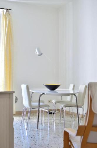 a dining room with a table and white chairs at The Family Houses - Apartments with Balcony and Lake View in Colonno