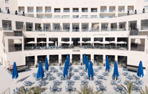 a view of a hotel with blue umbrellas and tables at Pickalbatros Palais Des Roses - Agadir - All Inclusive in Agadir