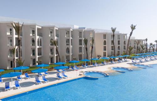 a resort with a pool and blue umbrellas and chairs at Pickalbatros Palais Des Roses - Agadir - All Inclusive in Agadir