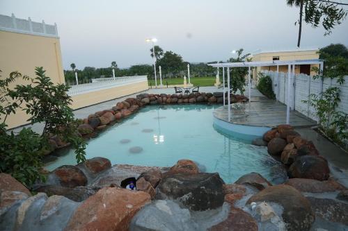 a swimming pool with a waterfall and rocks at Rajputana Palace with Private Pool by Homeyhuts in Hyderabad
