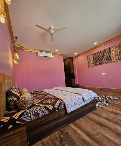 a bedroom with a bed with a pink wall at Rajputana Palace with Private Pool by Homeyhuts in Hyderabad