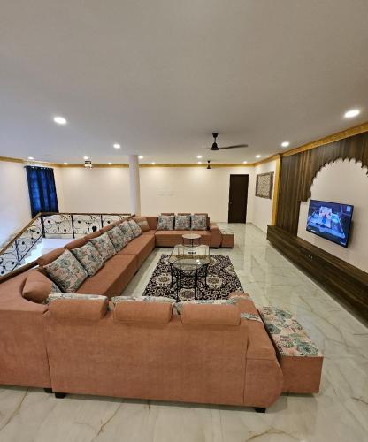 a large living room with a large couch and a tv at Rajputana Palace with Private Pool by Homeyhuts in Hyderabad