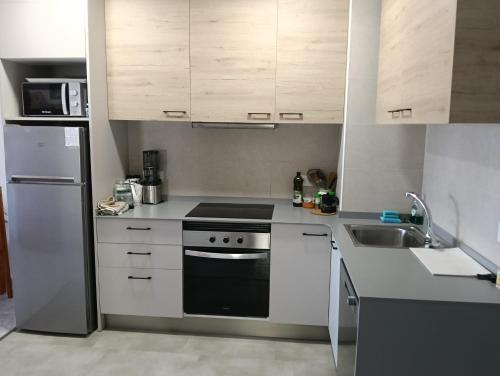 a kitchen with white cabinets and a stove and a sink at Apartamento en Blanes in Blanes