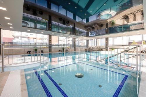 a large swimming pool in a building at Rewal Cozy Apartment with Parking, Gym, Spa & Pool close to the Beach by Noclegi Renters in Rewal