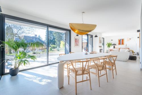 une salle à manger blanche avec une table et des chaises blanches dans l'établissement MENTHON- Villa W Architecte 2 pas du lac by LLA SELECTIONS, à Menthon-Saint-Bernard