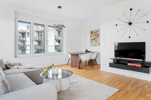 a living room with a couch and a tv and a table at EXQUIS Design 2BR Apartment HANSEN I Balcony I Mercedes & US Army I Parking I Stuttgart in Böblingen