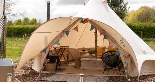 a tent with a table and chairs in a yard at Broadleaves Luxury Glamping in Ticknall