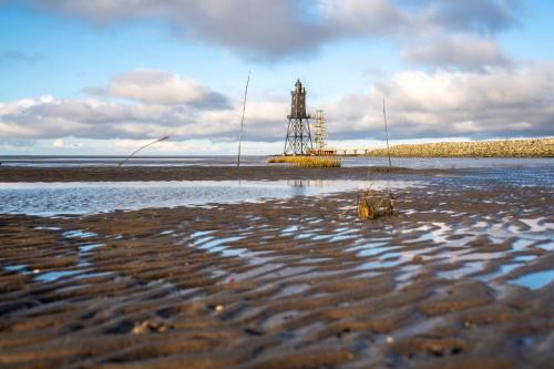 a beach with a clock tower in the water at Ferienhaus Knechtsand 09 in Dorum Neufeld