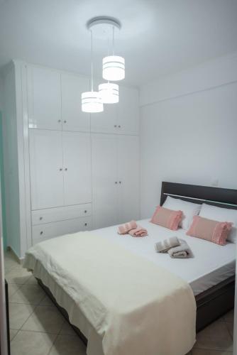 - une chambre blanche avec un grand lit et des oreillers roses dans l'établissement Sunset Waves, à Menídion