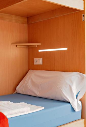 a bed in a small room with a wooden wall at Cruce de Caminos Arzúa in Arzúa