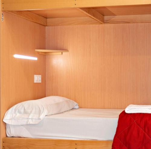 a bed in a room with a wooden wall at Cruce de Caminos Arzúa in Arzúa