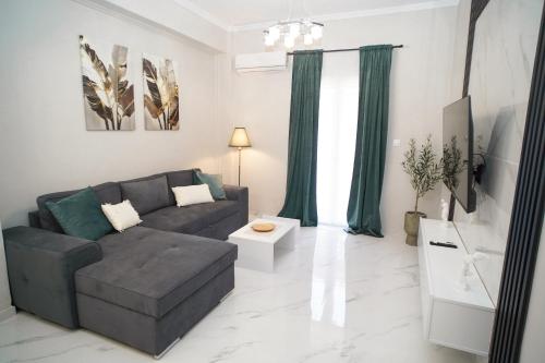 un soggiorno con divano grigio e tende verdi di Elarion Elegant Port Apartment a Città di Corfù
