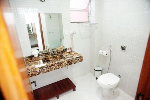 uma casa de banho branca com um lavatório e um WC em Pousada Emcanto em Vila Muriqui