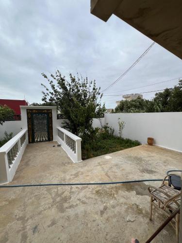 eine Terrasse mit einer weißen Mauer und einem Tor in der Unterkunft إقامة بدر in Asilah