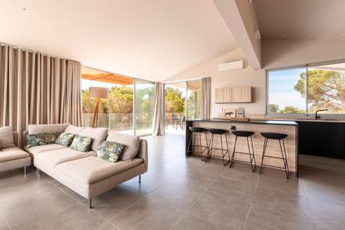 un salon avec un canapé et une cuisine dans l'établissement La Villa Pianottoli - Magnifique Vue Panoramique, à Pianottoli-Caldarello