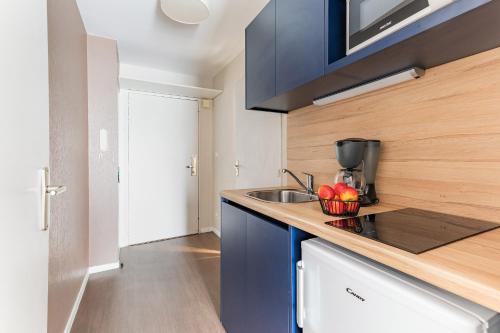 a small kitchen with blue cabinets and a sink at Appart'City Classic Nantes Quais de Loire in Nantes