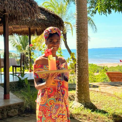 a woman is holding a tray with a banana at WINGS HOTELS in Nosy Be