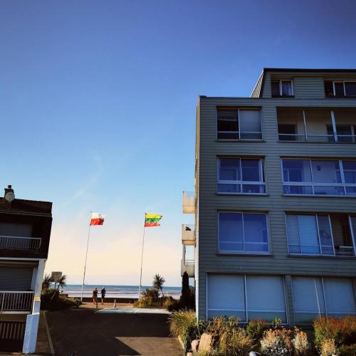 a building with three flags in front of the beach at Les pieds dans l'eau - loggia exposée plein sud in Courseulles-sur-Mer