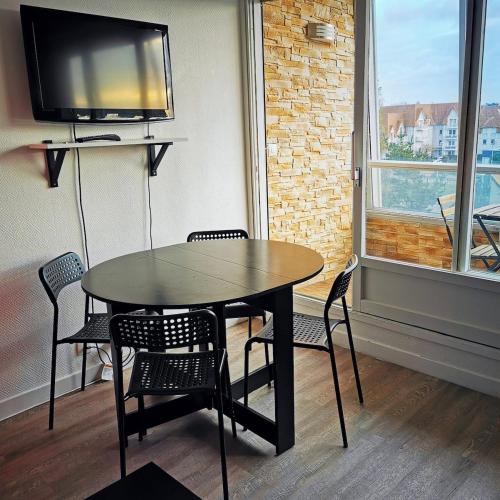 a dining room with a table and chairs and a tv at Les pieds dans l'eau - loggia exposée plein sud in Courseulles-sur-Mer