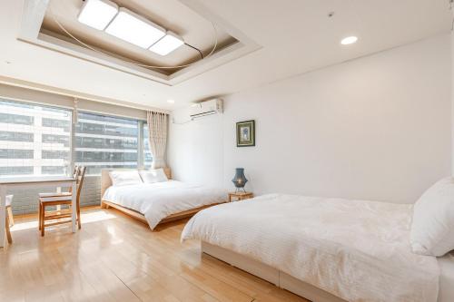 a bedroom with two beds and a chair and a window at Hongdae Sky apartment in Seoul