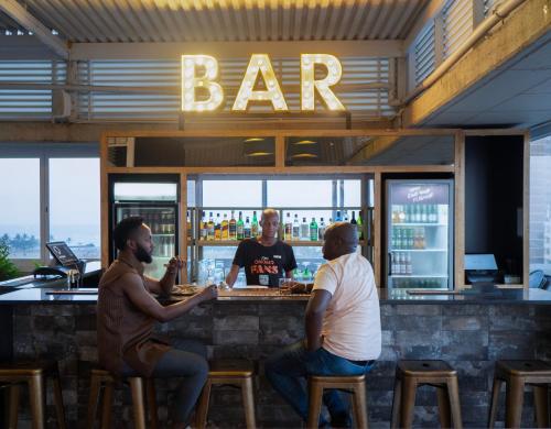 a group of three men sitting at a bar at ONOMO Hotel Durban in Durban