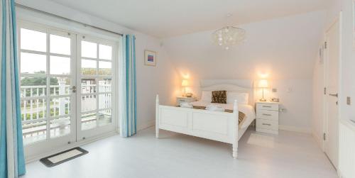 a white bedroom with a bed and a window at 5 The Sanctuary, Thorpeness - Aldeburgh Coastal Cottages in Thorpeness