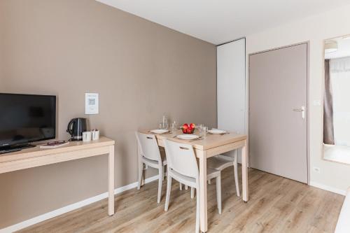 a dining room with a table and chairs and a television at Appart'City Classic Nantes Quais de Loire in Nantes