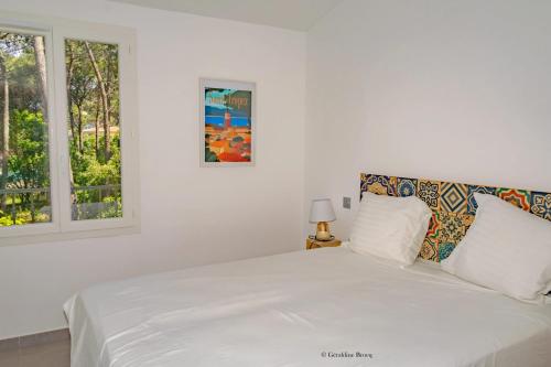 un lit blanc dans une chambre blanche avec une fenêtre dans l'établissement Villa confortable à Sainte-Maxime avec piscine privée, à Sainte-Maxime