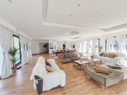 Il comprend un grand salon doté d'un mobilier blanc et de grandes fenêtres. dans l'établissement Maison 12 personnes, Vendée et puy du fou, à Treize-Septiers