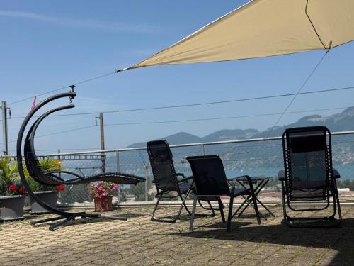 a group of chairs and an umbrella on a patio at Swiss Apartment Thunersee in Einigen