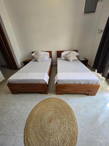 two beds sitting in a room with a rug at Smile Boutique Beach hotel in Nungwi