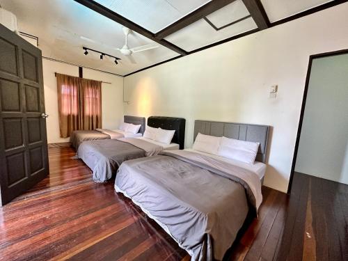 two beds in a room with wooden floors at Homestay The Wooden Port Dickson in Port Dickson
