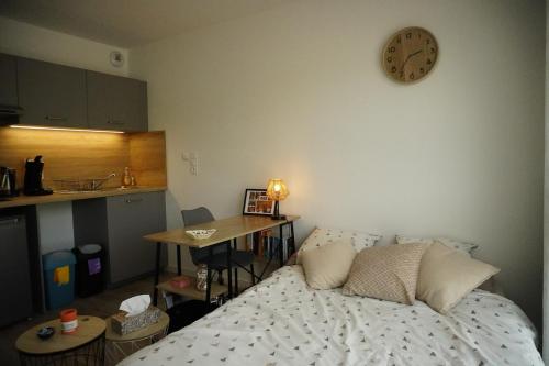 une chambre avec un lit et une horloge au mur dans l'établissement Logement neuf - cœur de ville, à La Roche-sur-Yon