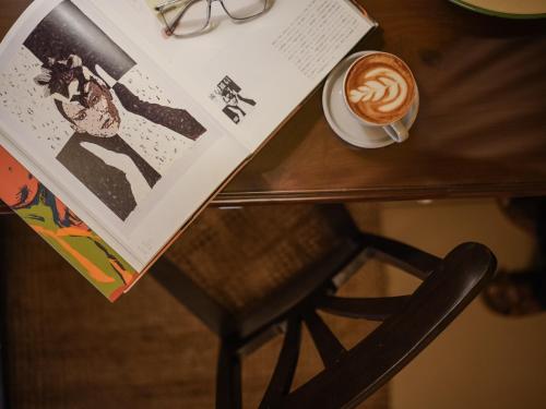 a table with a cup of coffee and a magazine at The Project Cafe and Hotel in Aldona