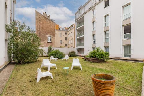 a yard with white chairs and a table and buildings at Appart'City Classic Nantes Quais de Loire in Nantes