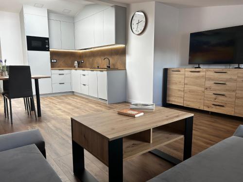a living room with a table and a kitchen with a tv at Loft Apartments Bielawa "Wschód Słońca" Polskie Como Góry Sowie in Bielawa