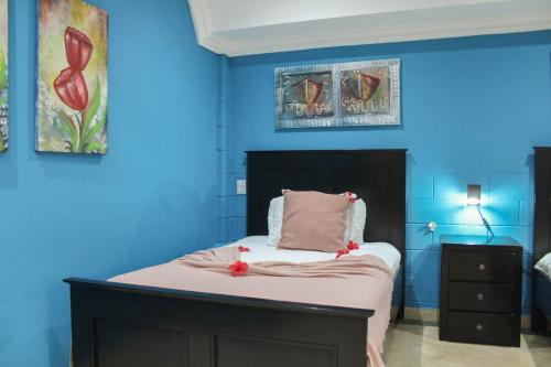 a blue bedroom with a bed with red flowers on it at hotel plaza BRISAS MT in Punta Cana